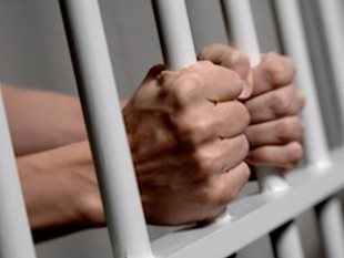 Hands sticking through bars of jail cell