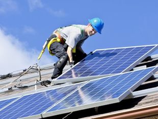 Worker installing solar panel on roof