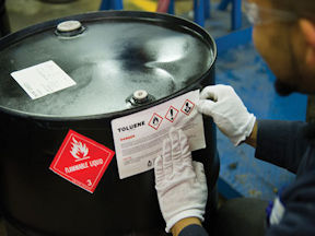 Worker applies a label on a hazardous workplace product