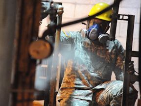 Construction worker wearing hard hat, safety goggles and respirator