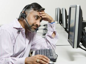 Stressed worker wearing headset and looking at computer screen