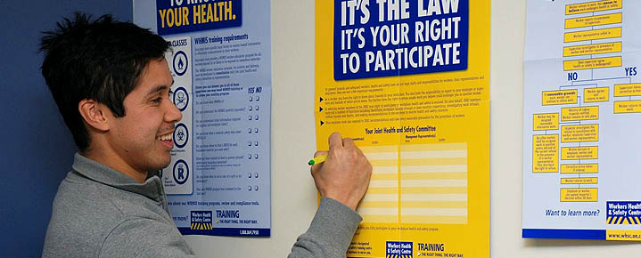 Worker reviews WHSC health and safety posters on the right to know, right to participate and right to refuse unsafe work