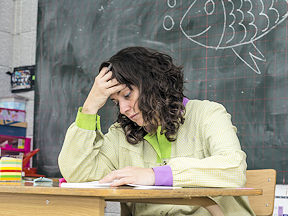 Teacher hands head after facing workplace violence and harassment