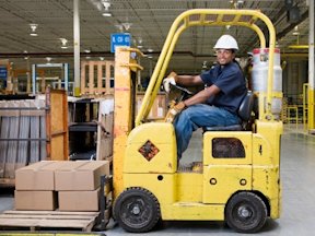 Worker driving a lift truck in a warehouse