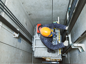 Lift machinist repairing elevator in lift shaft