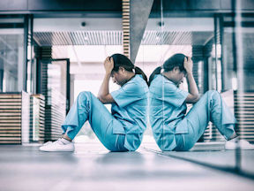 Healthcare worker sits on the floor after facing abuse