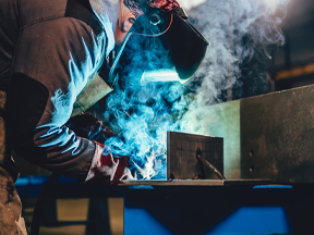 Industrial welder with torch and protective helmet