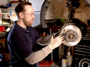 Mechanic replacing brake pads while wearing safety glasses