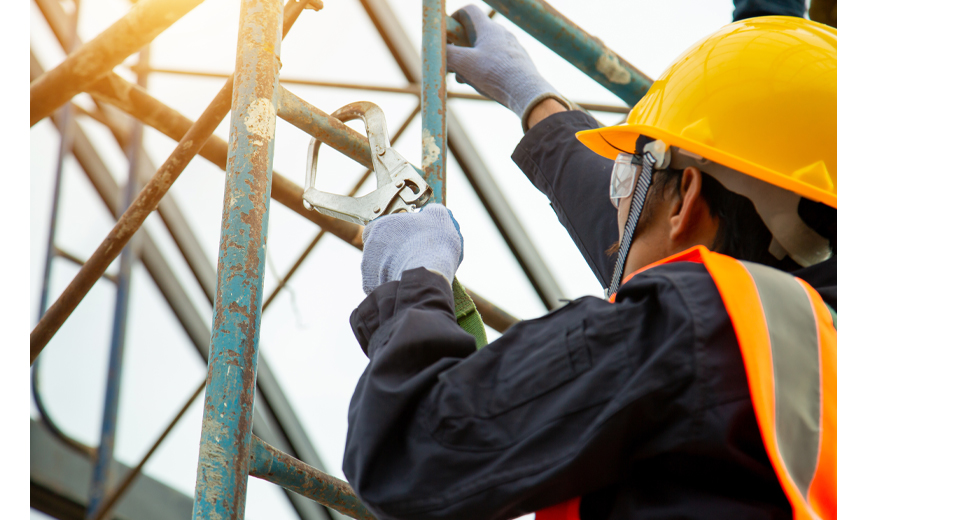 A man with a hardhat works on top of a ladder.