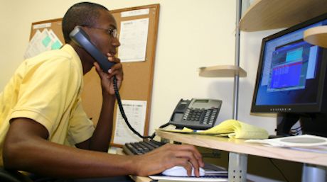 a WHSC employee answering a phone call and reading information on a computer screen