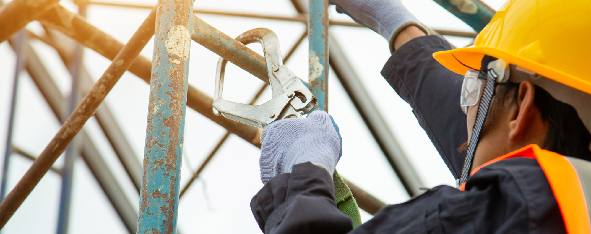 A man with a hardhat works on top of a ladder.